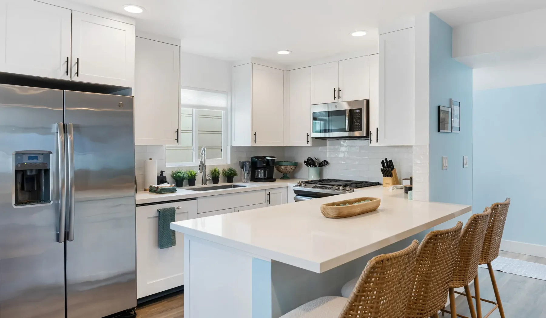 Una cocina luminosa con gabinetes blancos, electrodomésticos de acero inoxidable y una isla grande.