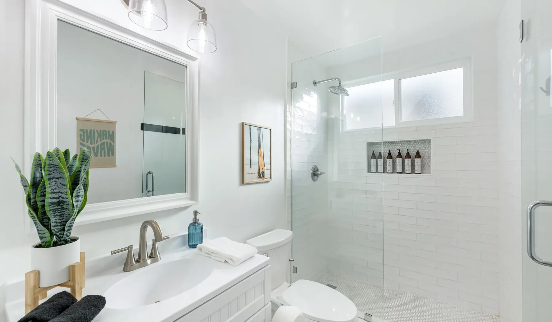 Un baño luminoso con lavabo, inodoro y ducha de vidrio.