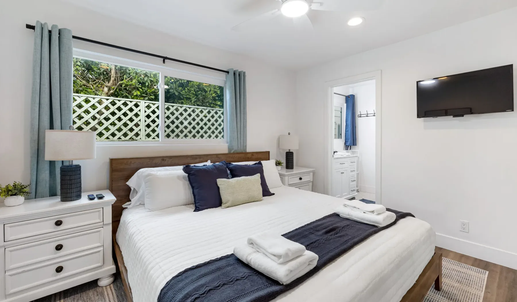 Un dormitorio luminoso con una cama bien tendida y una ventana con vistas a la vegetación.