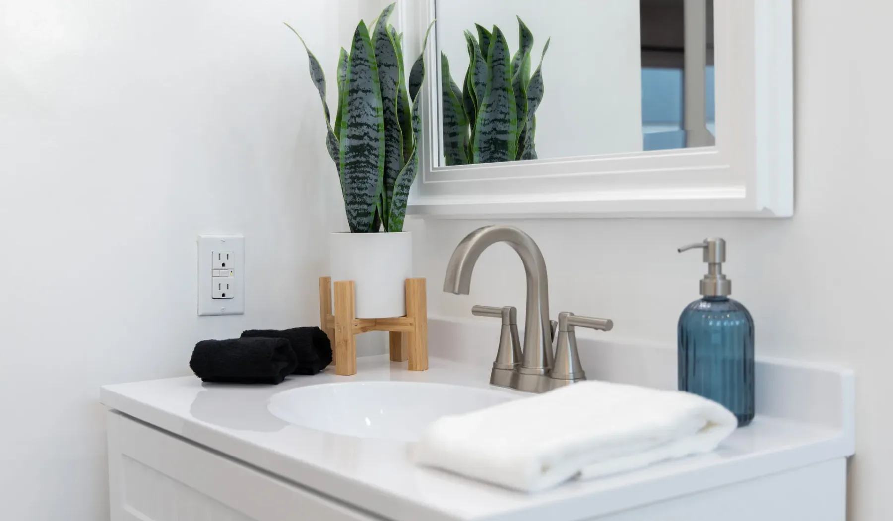 Un lavabo de baño con toallas dobladas y una planta en maceta.