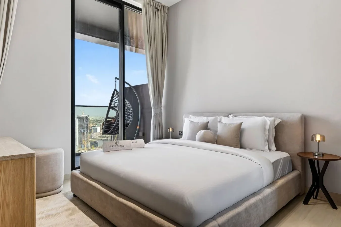 Un dormitorio con una cama bien arreglada junto a una ventana de suelo a techo.