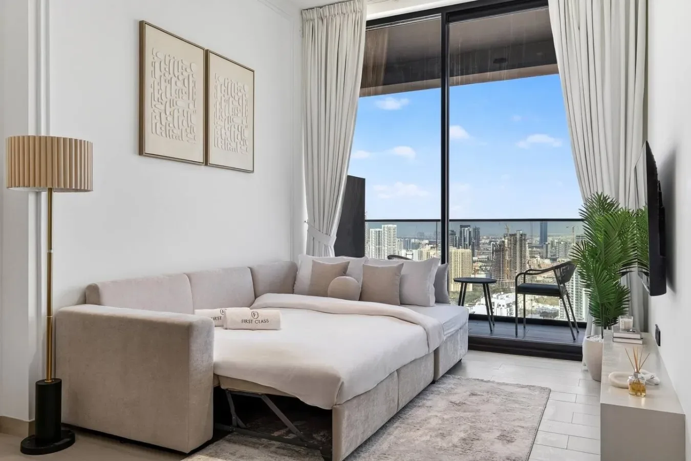 Una sala luminosa con un sofá junto a una gran ventana con vistas a la ciudad.