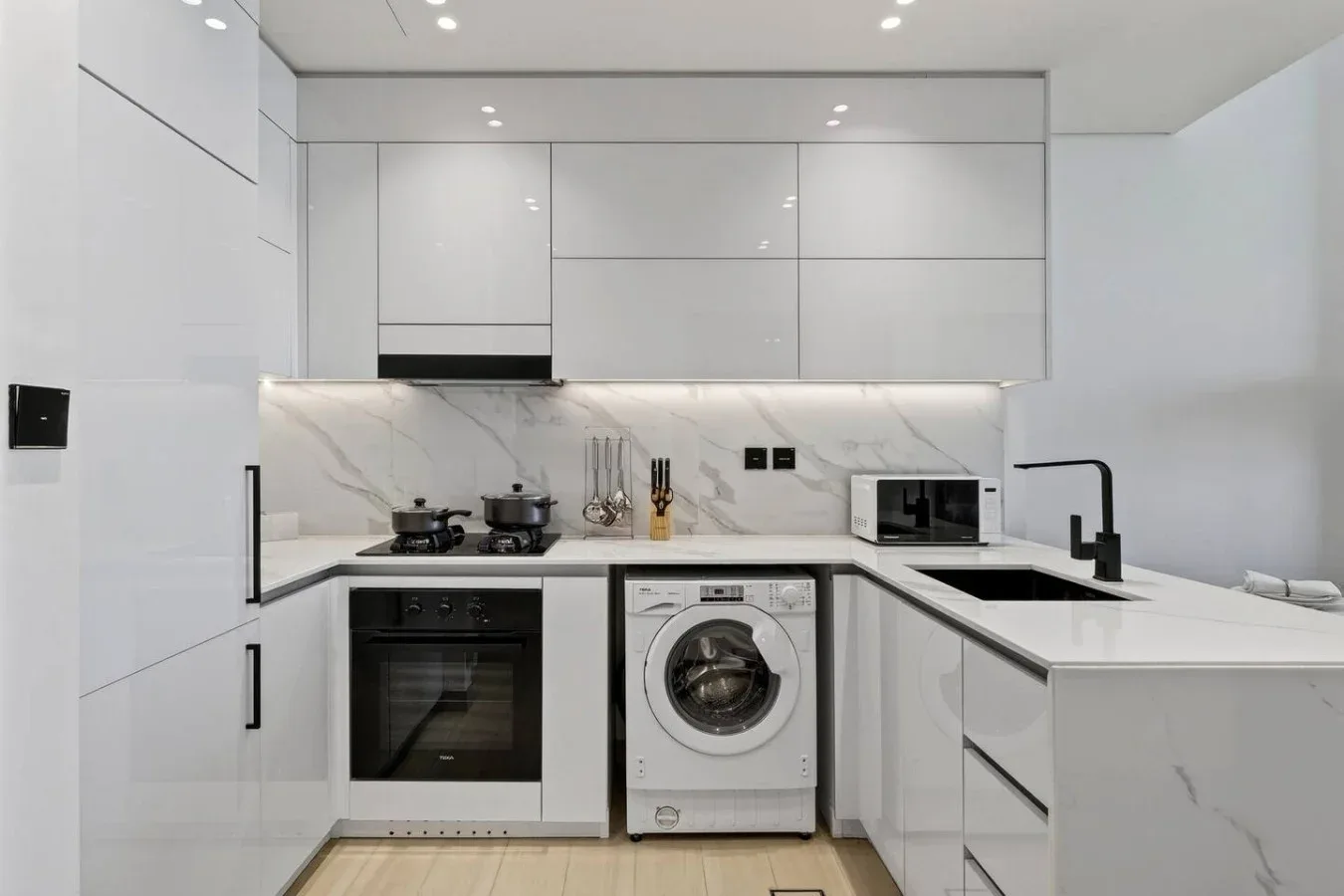 Una cocina blanca moderna con una lavadora bajo la encimera.