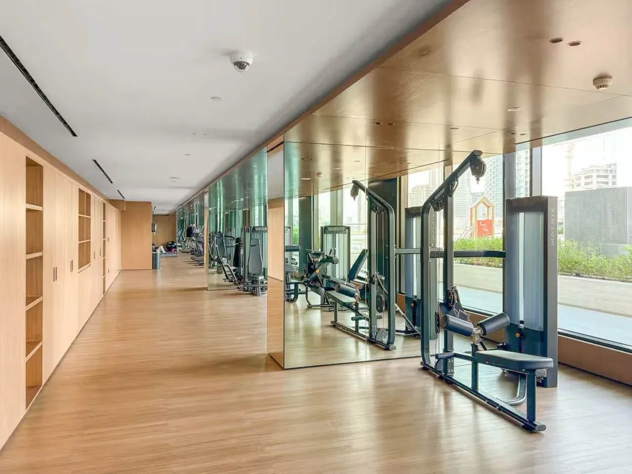 Un gimnasio con máquinas de ejercicio junto a grandes ventanales.