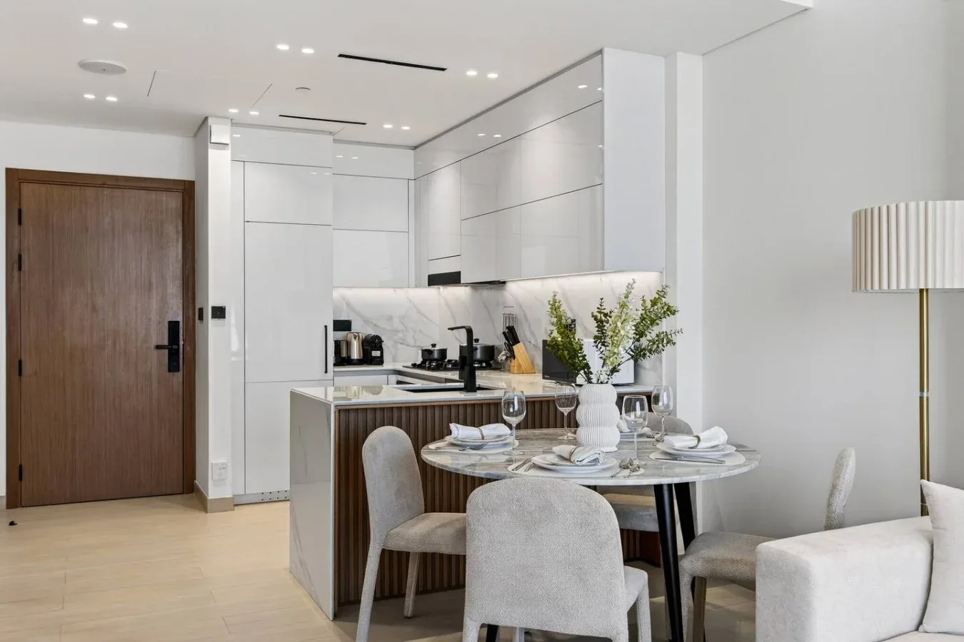 Un comedor moderno con una mesa puesta junto a una cocina compacta.