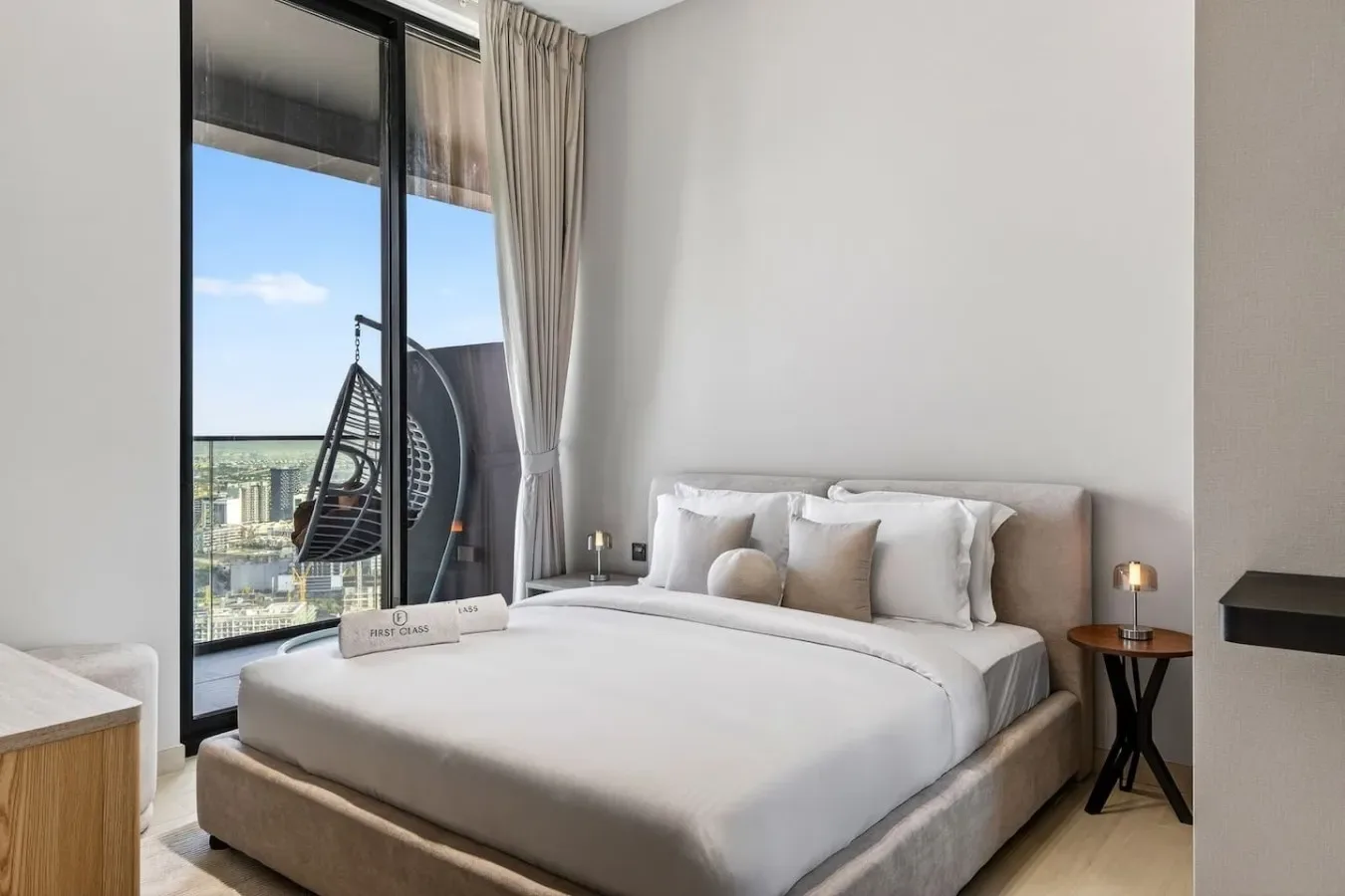 Un dormitorio con una cama bien tendida junto a una ventana grande.
