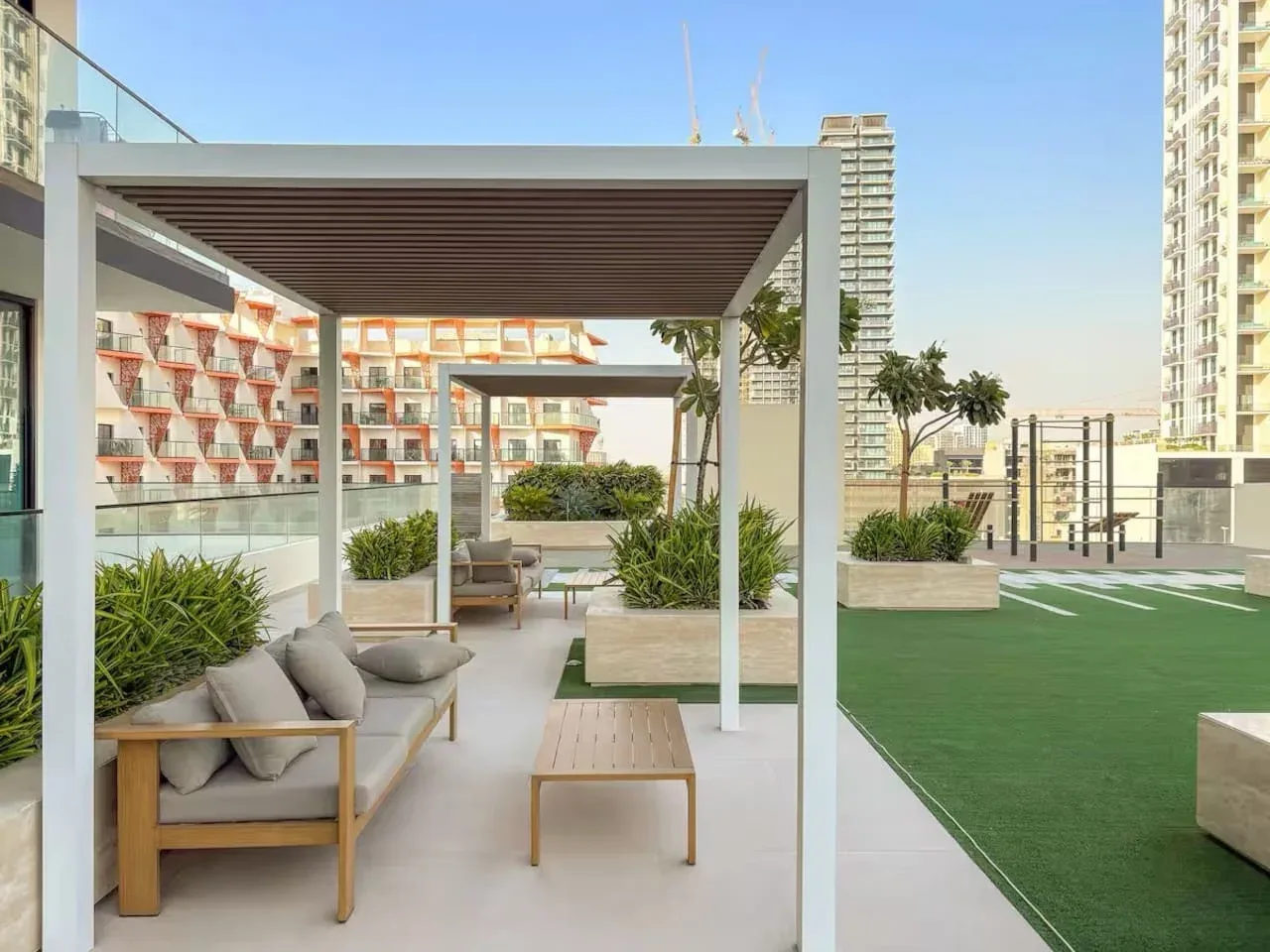 Una terraza en la azotea tiene asientos cubiertos junto a una zona verde.