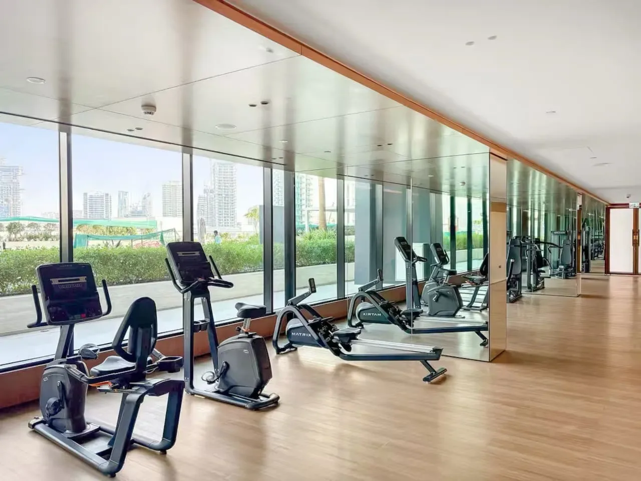 Un gimnasio con máquinas de ejercicio junto a ventanas de piso a techo.