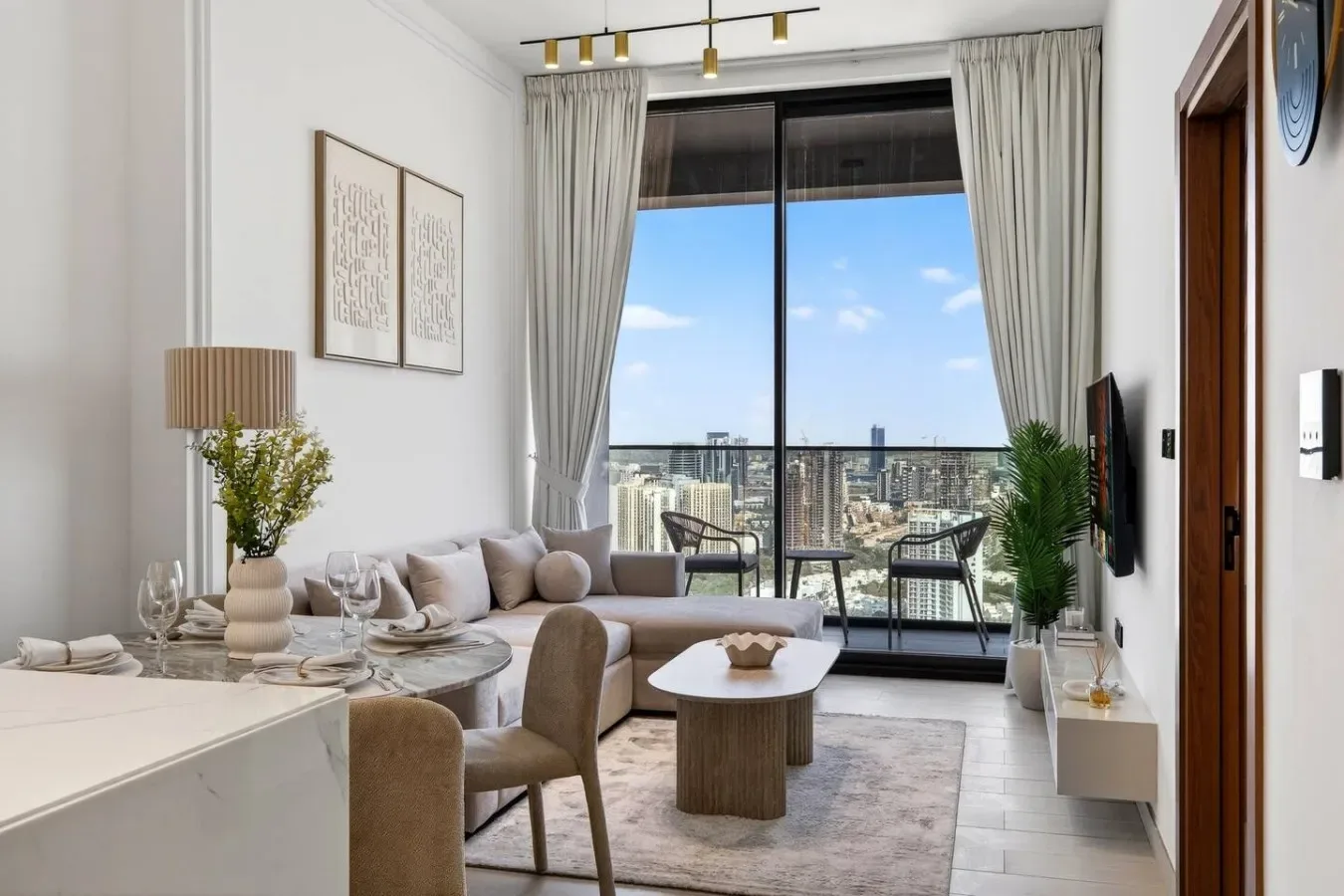 Una sala luminosa con una zona de estar frente a grandes ventanales y vistas a la ciudad.