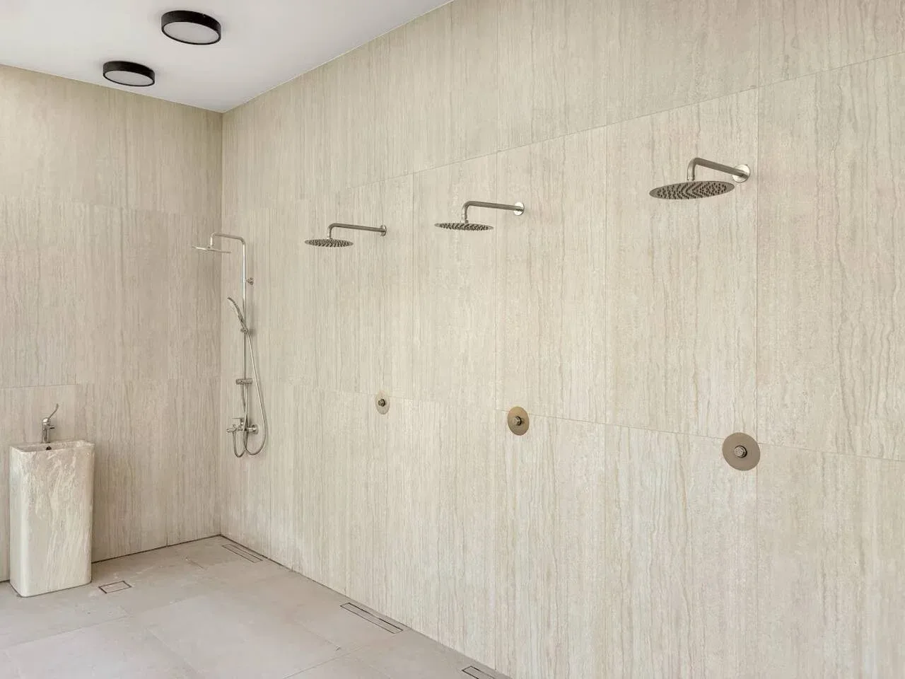 Una zona de ducha alicatada con varios accesorios de ducha en la pared.