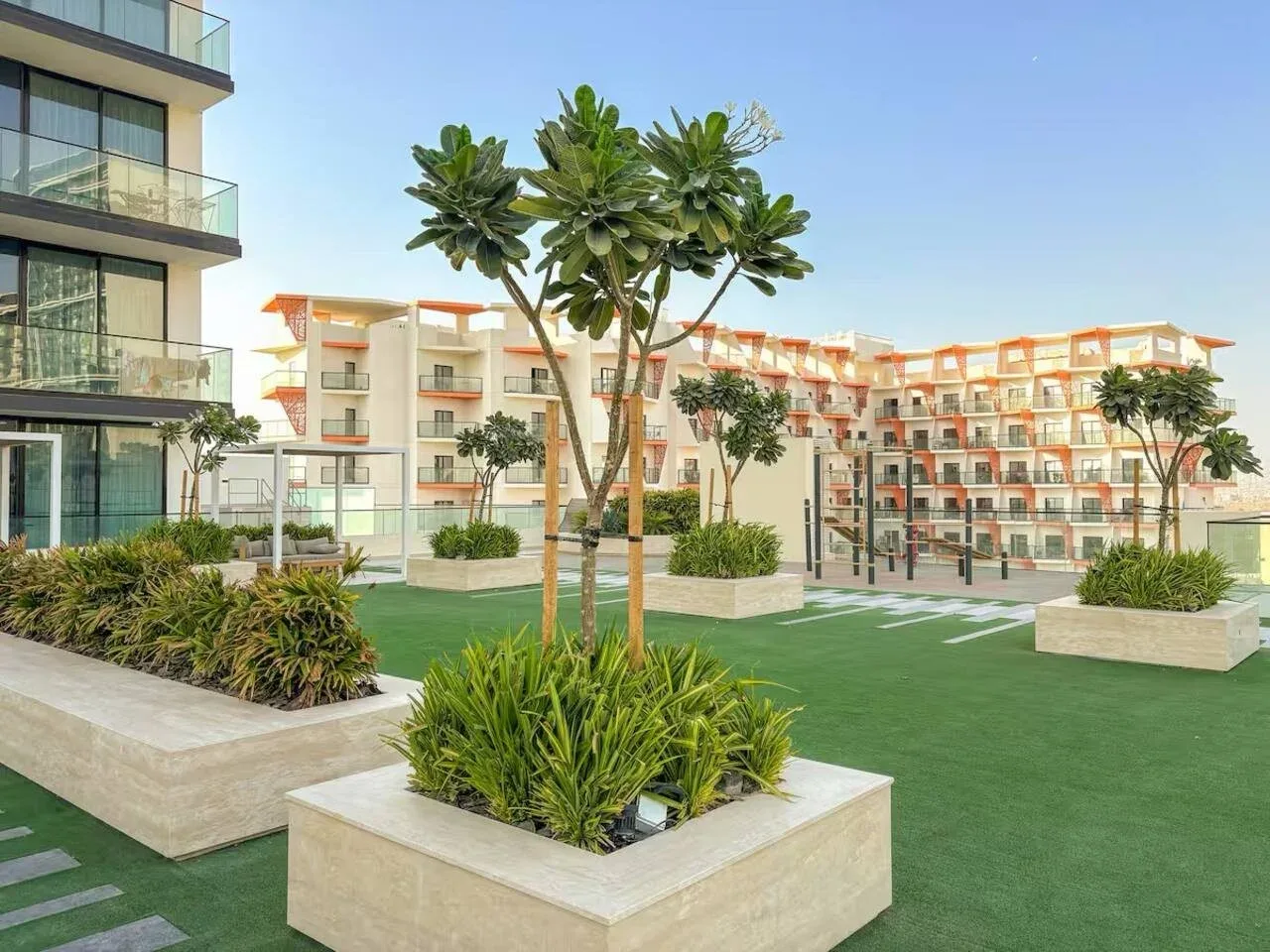 Un patio ajardinado con jardineras elevadas y edificios residenciales al fondo.