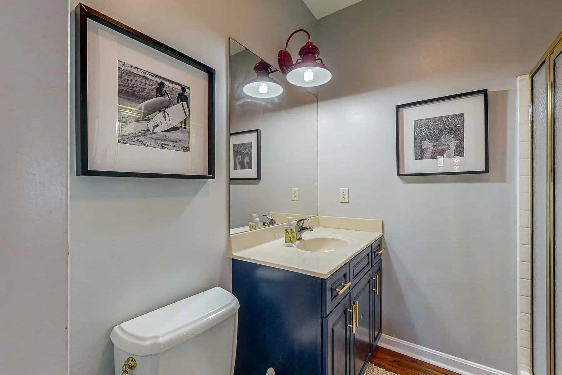 A bathroom with a vanity, sink, and framed wall art.