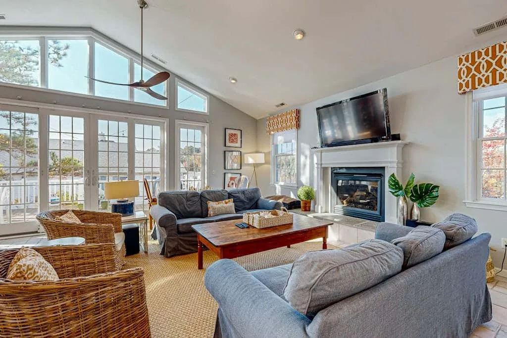 A bright living room with seating arranged around a coffee table and fireplace.