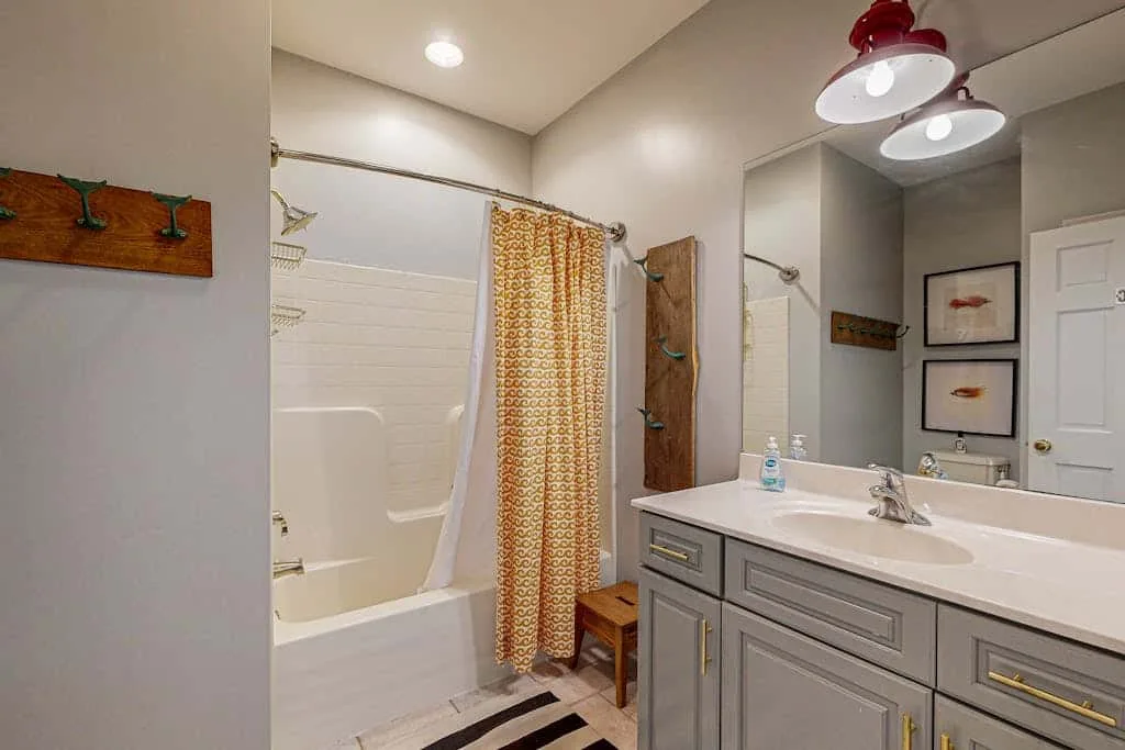 A bathroom with a bathtub, patterned shower curtain, and vanity.