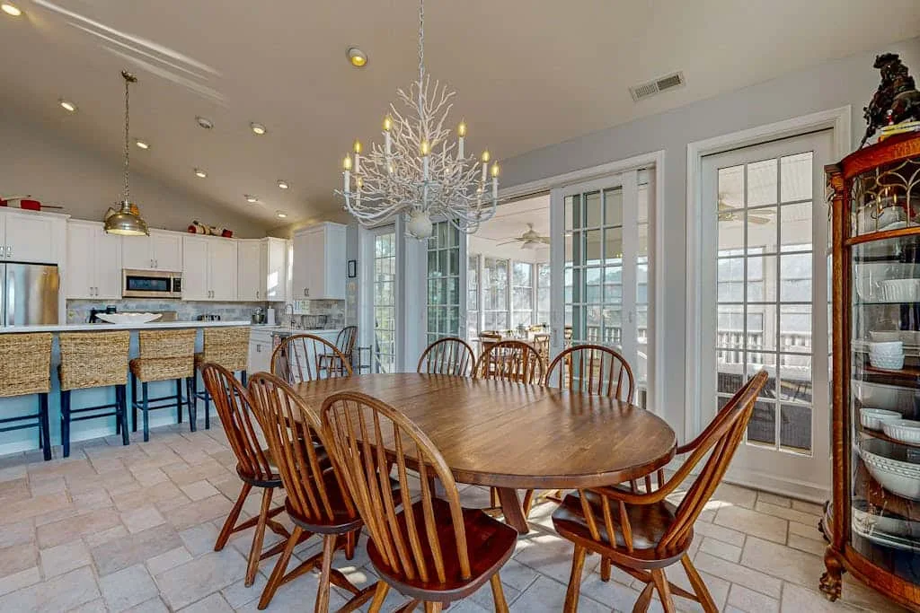 A dining area with a large wooden table and an open kitchen beyond.