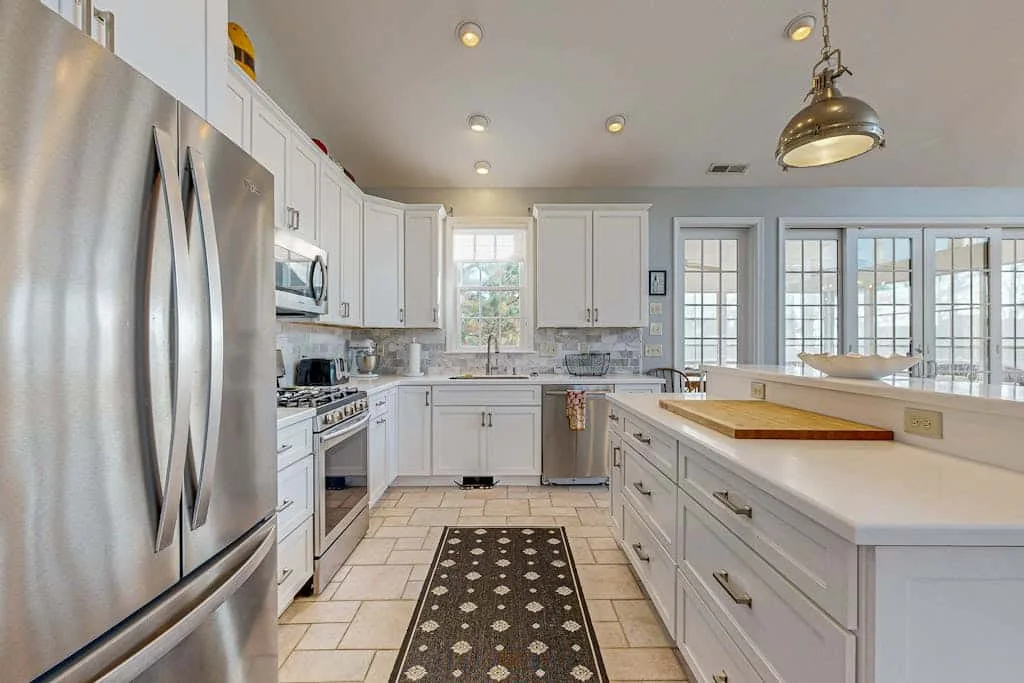 A bright kitchen features white cabinetry, stainless steel appliances, and a central island.