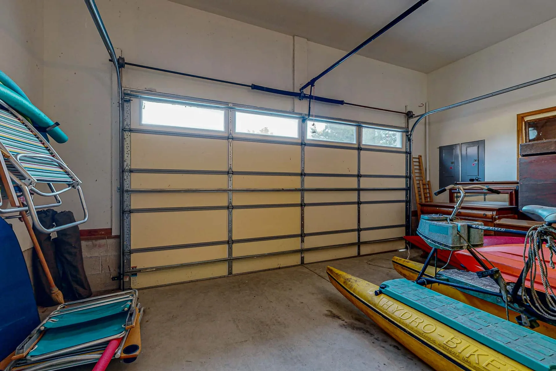 A garage interior with a large segmented door and stored watercraft.