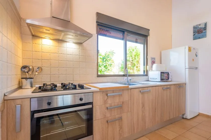A bright kitchen with wood cabinets, a stove, and a window above the counter.