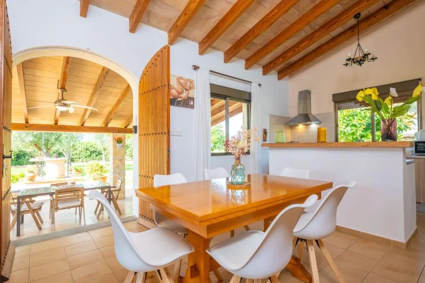 A dining area with a wooden table and chairs beneath exposed ceiling beams.