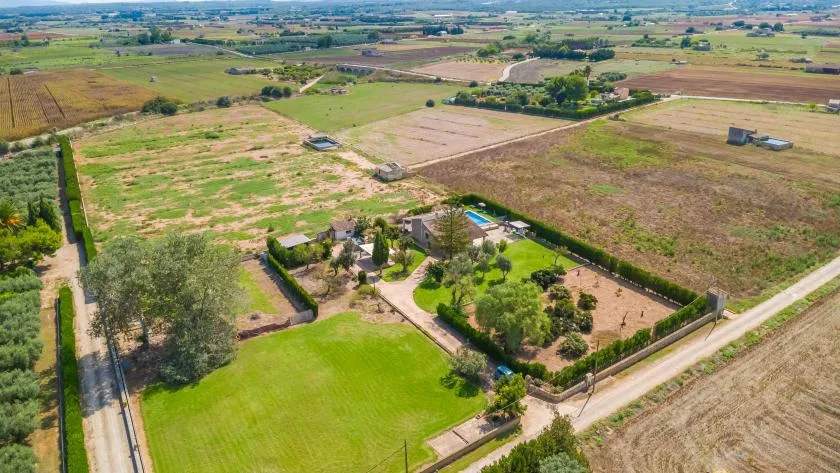 An aerial view of a rural property surrounded by fields, with a green lawn and trees.