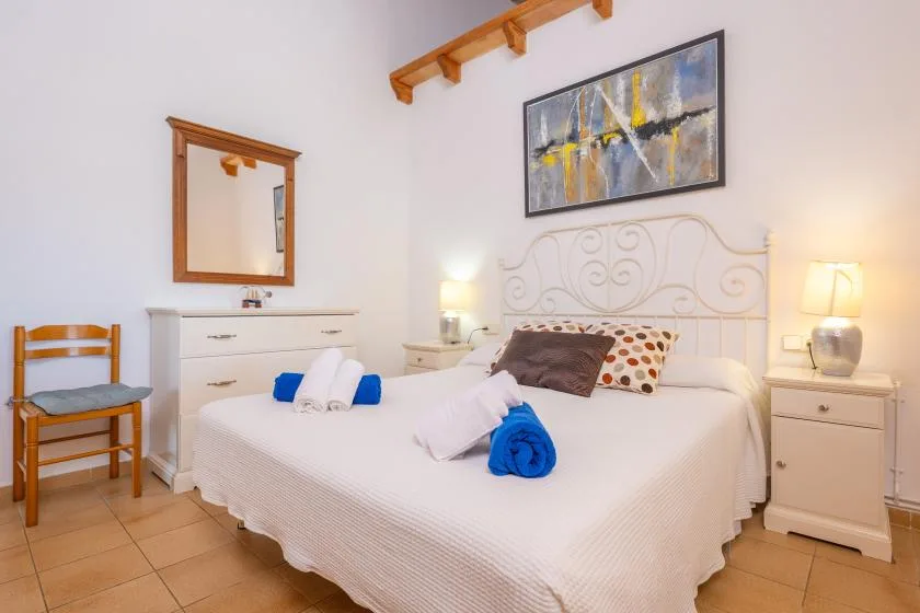 A bedroom with a bed, bedside tables, and framed artwork above the headboard.