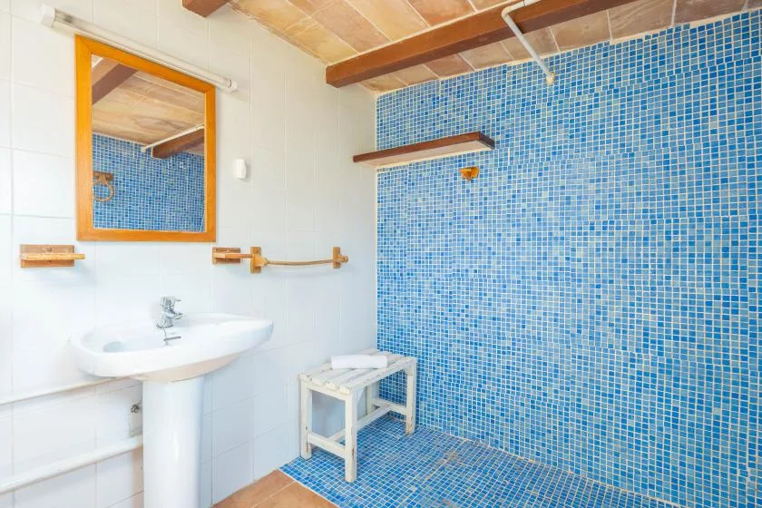 A bathroom with a sink beside a blue tiled shower area.