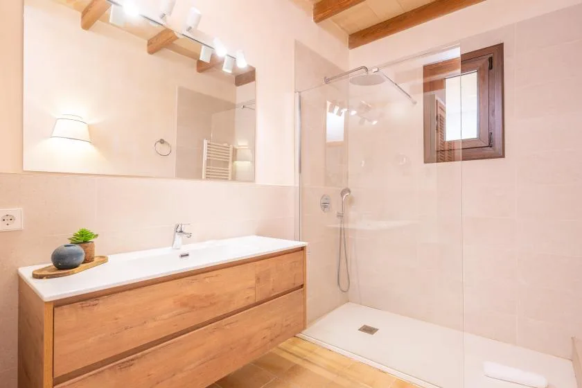 A bright bathroom with a long vanity and glass shower.