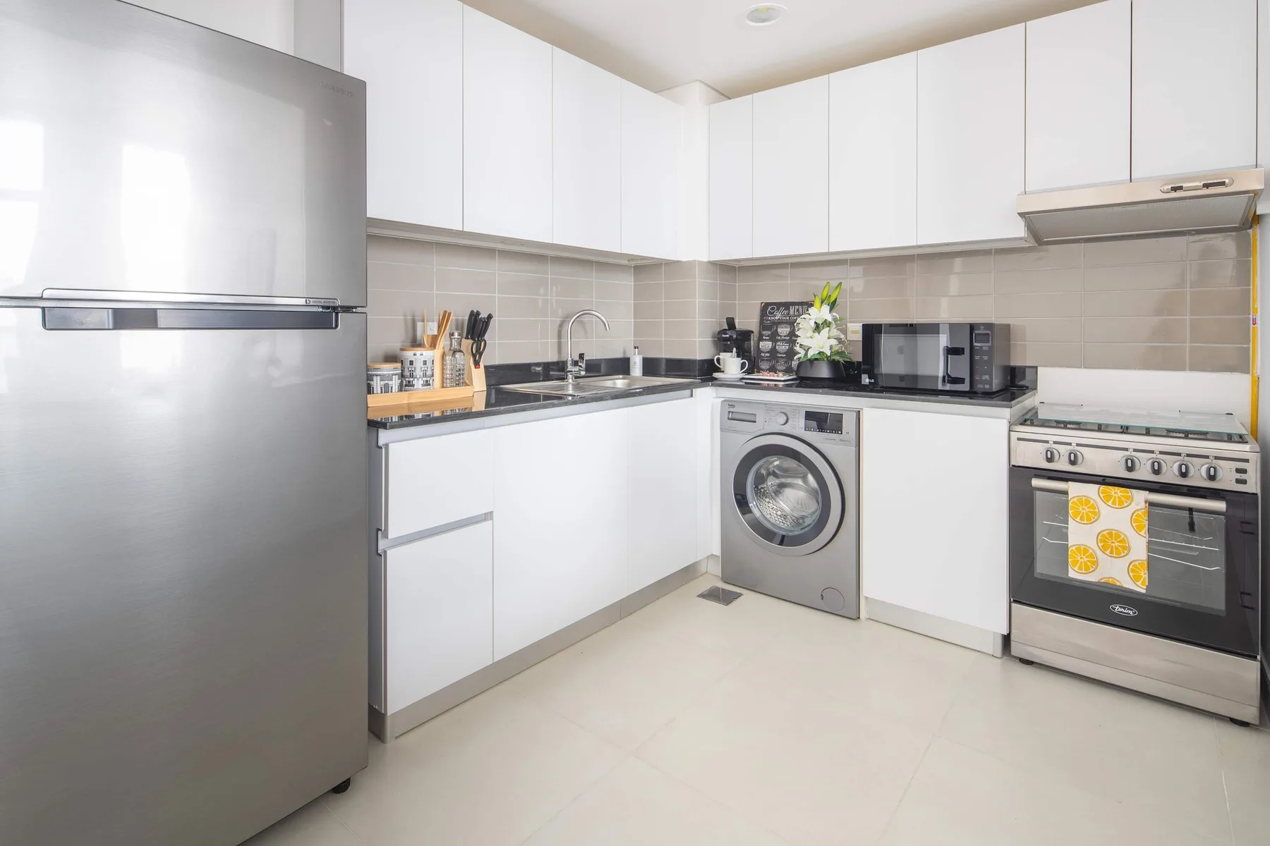 Una cocina moderna y luminosa con armarios blancos, un refrigerador y electrodomésticos.