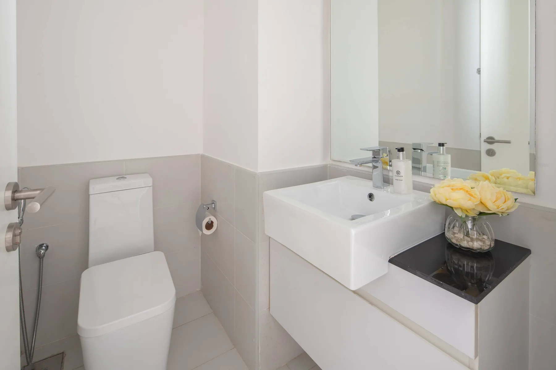 Un baño con lavabo, inodoro y espejo sobre la encimera.