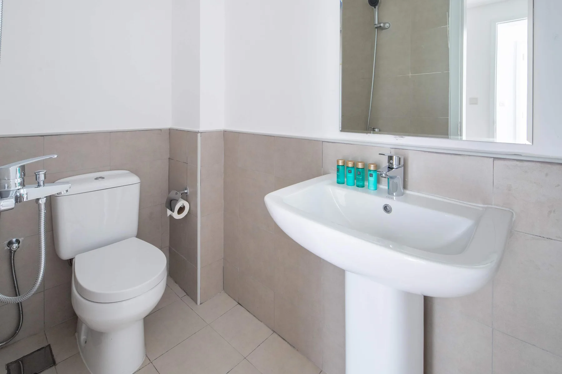 Un baño luminoso con inodoro, lavabo con pedestal y espejo.