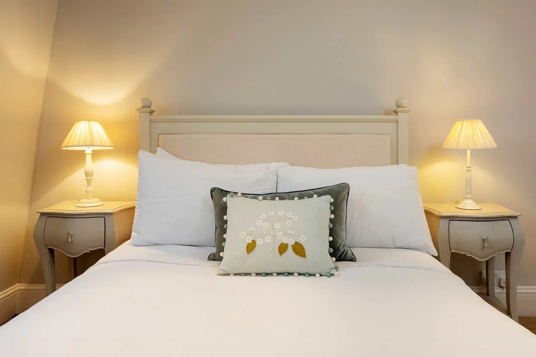 A neatly made bed with bedside tables and matching lamps.