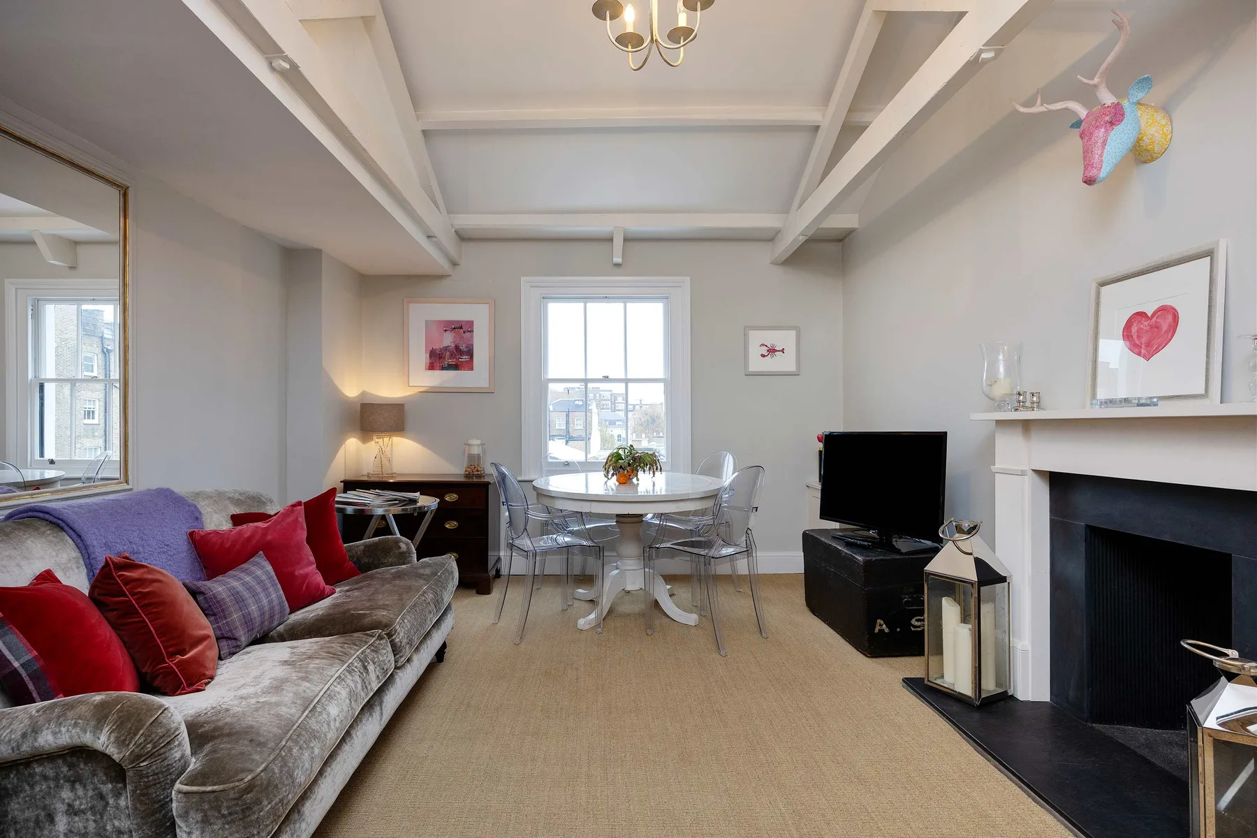 A bright living and dining room with seating, a dining table, and a television.
