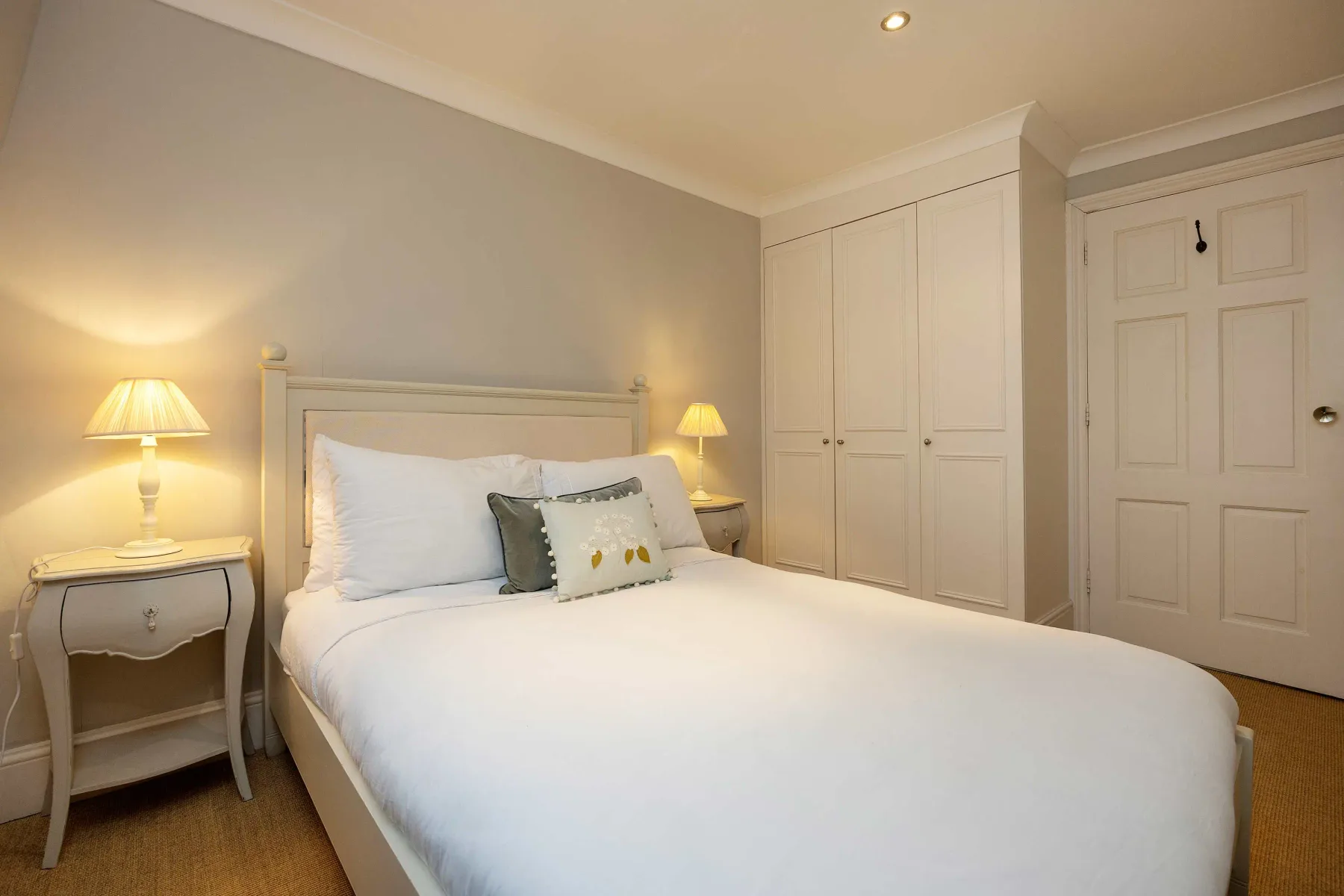 A bedroom with a neatly made bed and bedside tables.