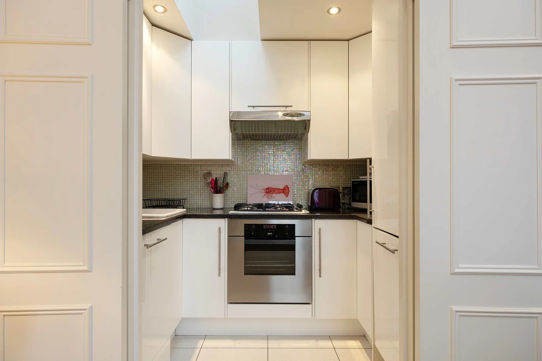 A compact kitchen with white cabinets and a tiled backsplash.