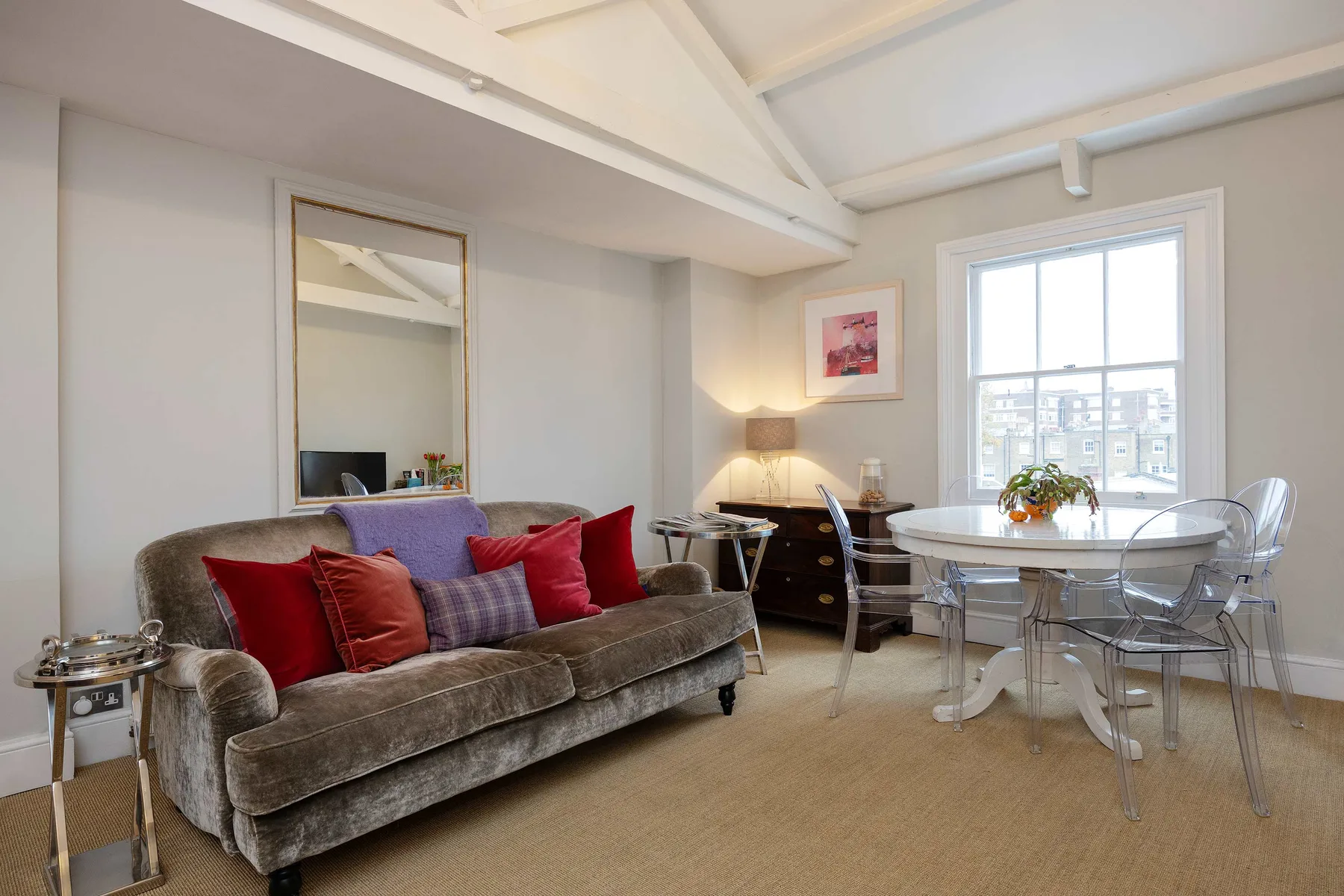 A bright living and dining area with a sofa, table, and large window.