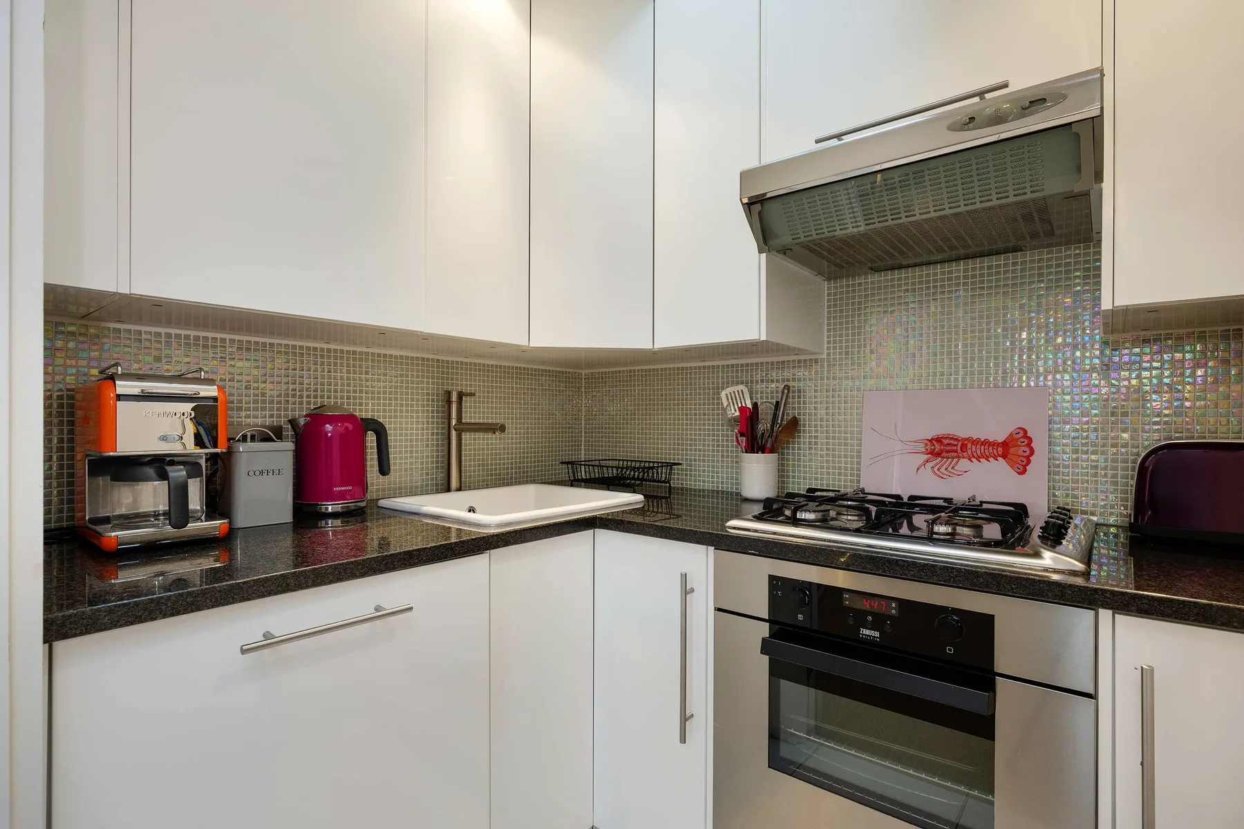 A modern kitchen with white cabinets, a cooktop, and an oven.