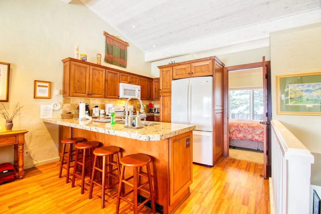 A bright kitchen with wooden cabinets, a central island, and bar stools.