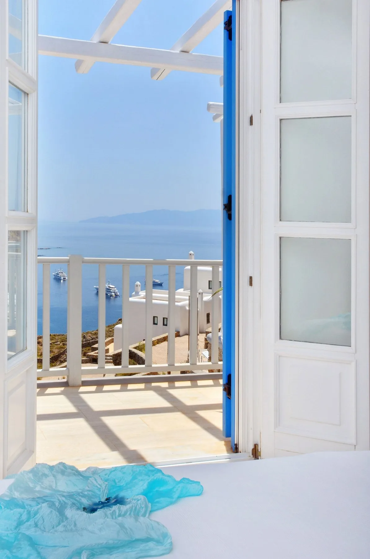 An open doorway overlooks a balcony and the sea.