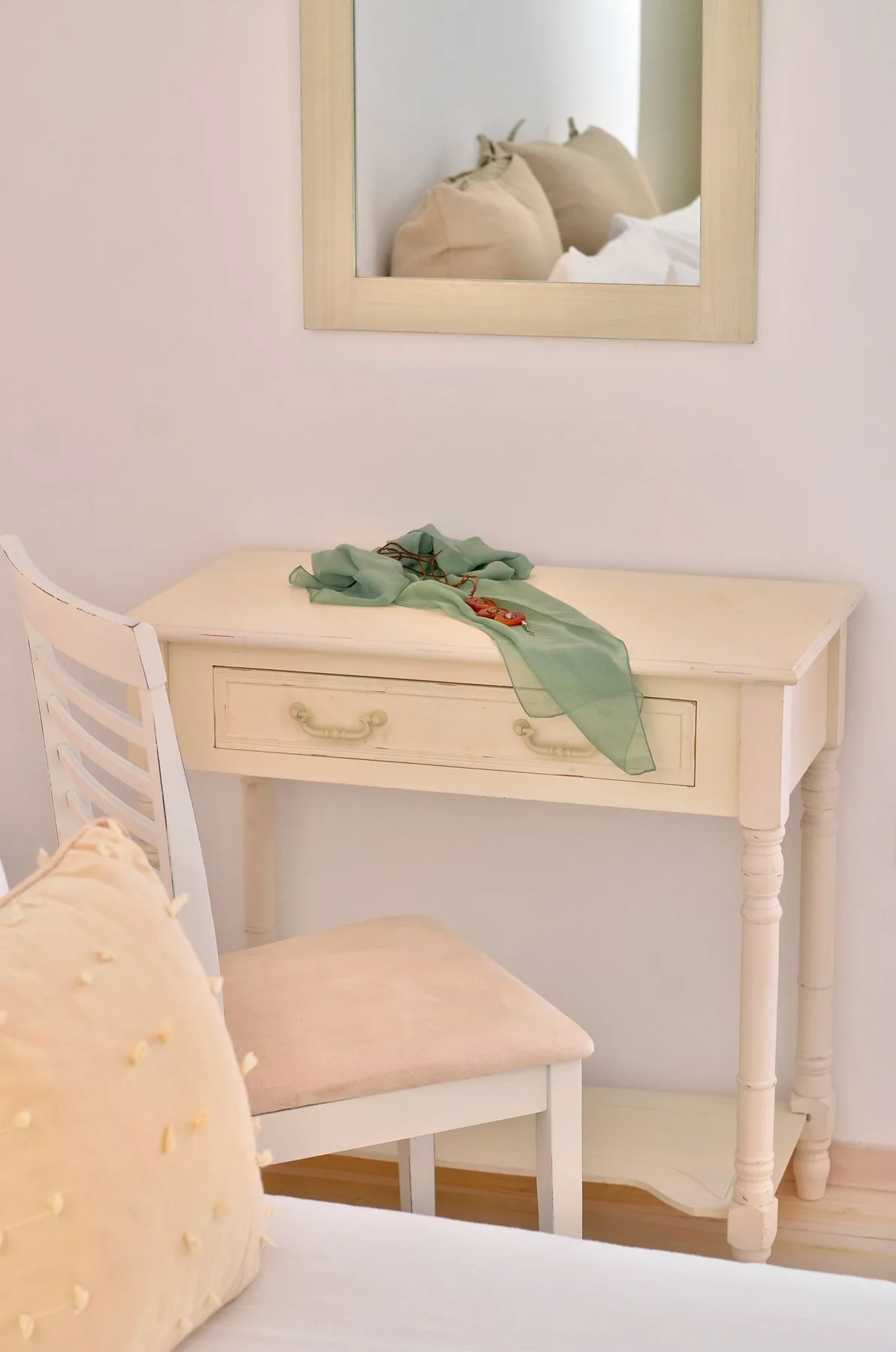 A small dressing area with a desk, chair, and mirror.