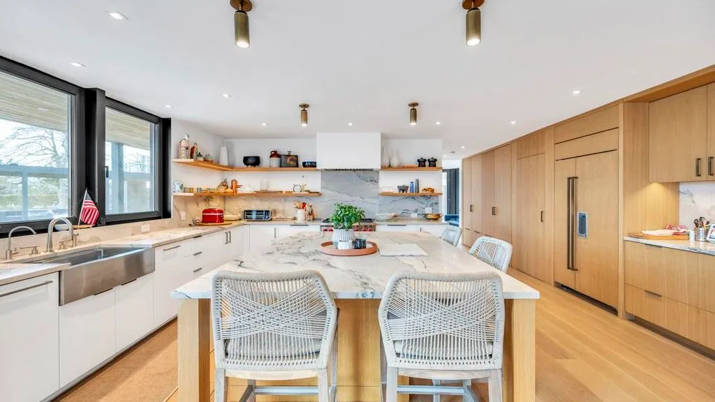 Una cocina y comedor luminosos con una mesa larga y gabinetes de madera clara.