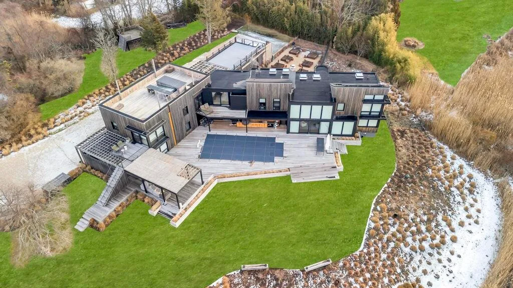 Una casa moderna con un amplio césped y paneles solares en el techo.