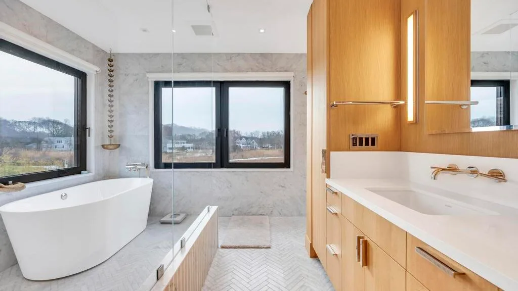Un baño luminoso con bañera exenta, ducha de vidrio y un largo tocador.