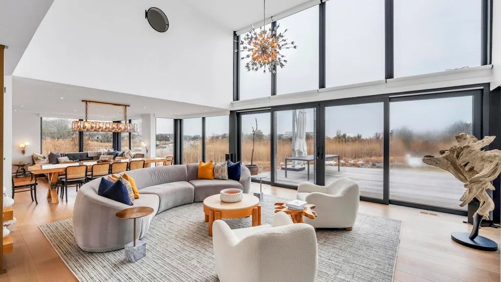 Una luminosa sala de estar con asientos y grandes ventanales con vistas al paisaje.