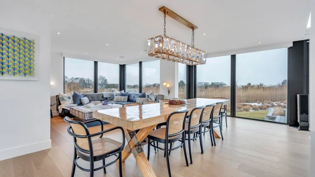 Un comedor luminoso con una mesa larga y grandes ventanales que dan al paisaje.