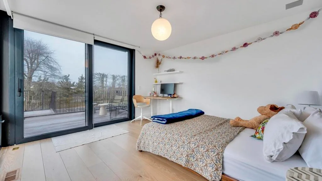 Un dormitorio con una cama junto a grandes puertas corredizas de vidrio que dan a un balcón.