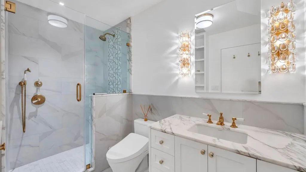 Un baño luminoso con ducha de vidrio, inodoro y tocador.