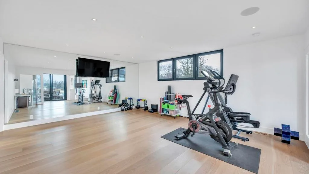 Un gimnasio luminoso con máquinas de ejercicio y una pared con espejo.