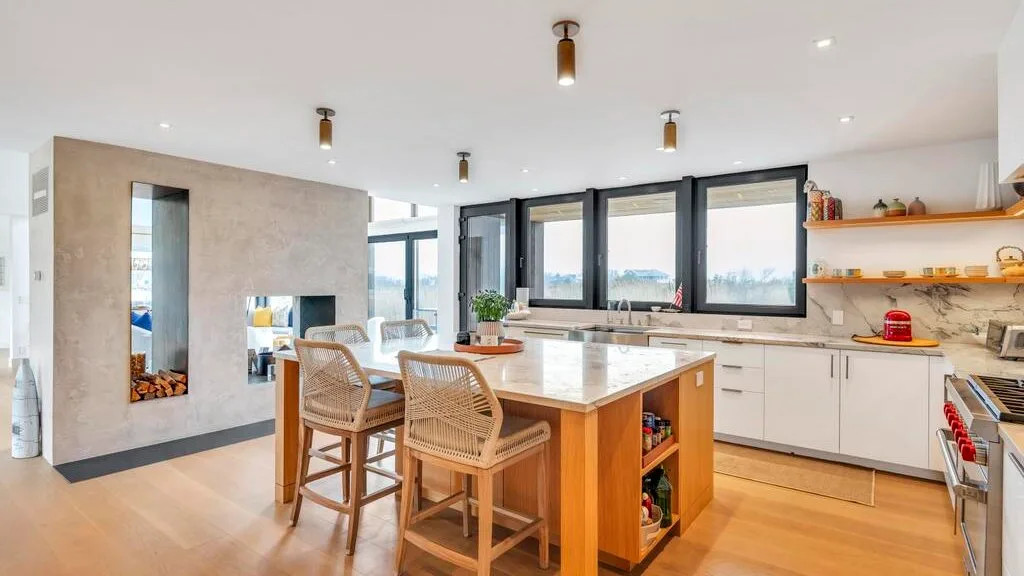 Una cocina luminosa con una isla central y grandes ventanas.