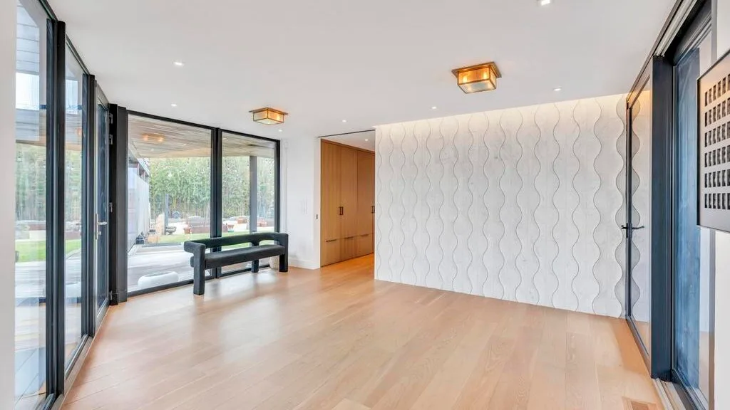 Una habitación amplia y luminosa con grandes ventanas y una pared blanca estampada.