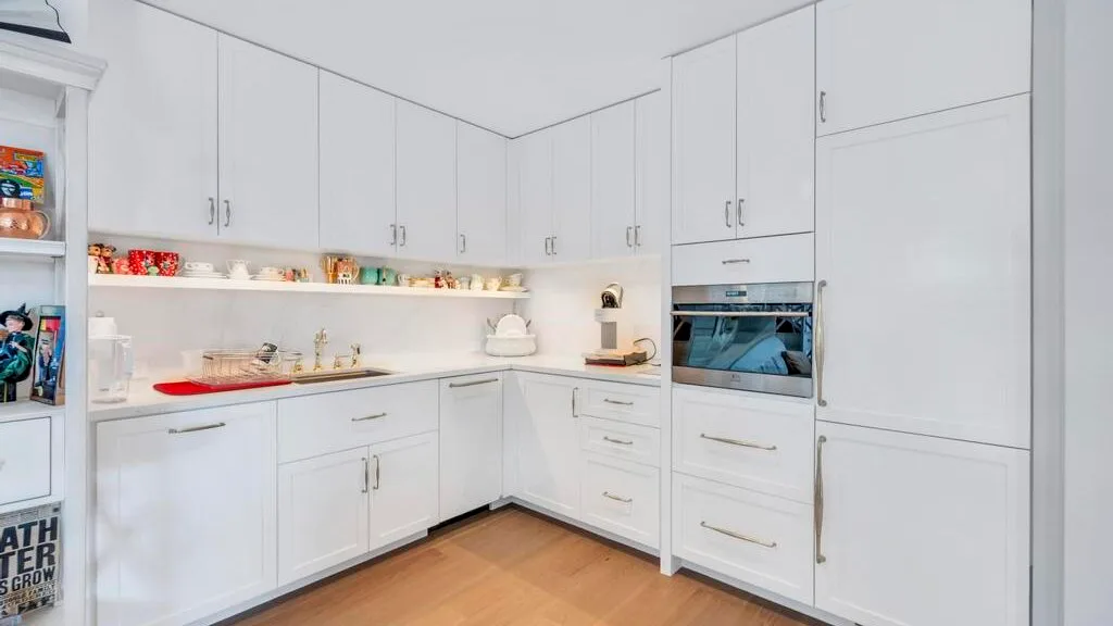 Una cocina blanca y luminosa con armarios empotrados y un horno.